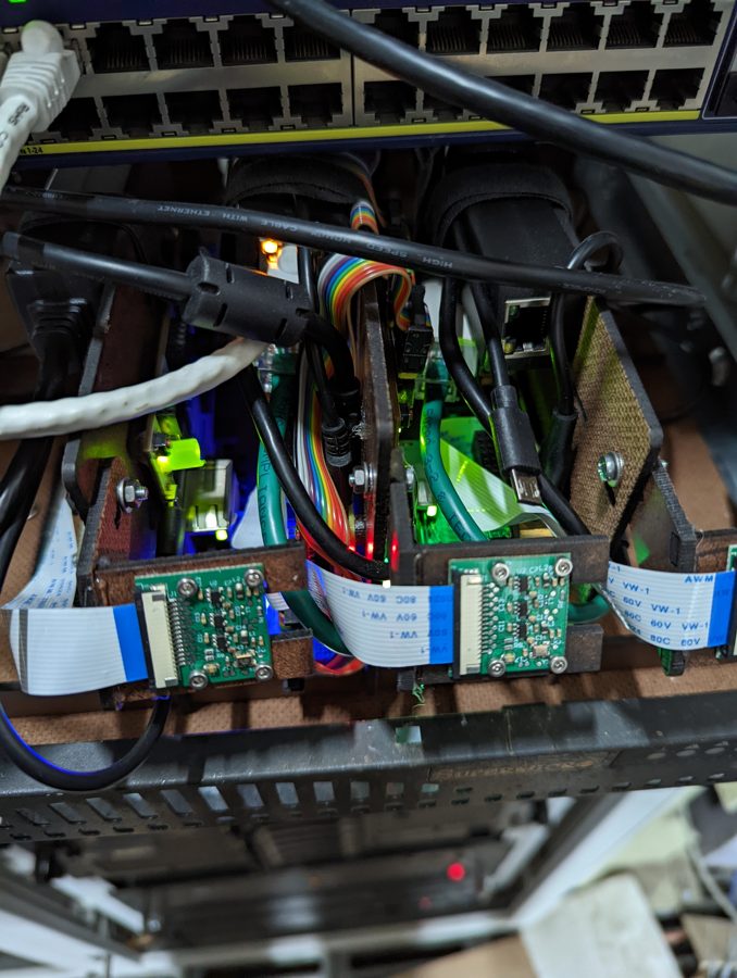 Close-up of Raspberry Pis, cameras and ribbon cables wired to the PoE switch